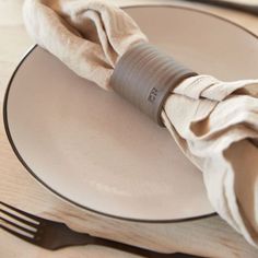 a white plate topped with a napkin next to a fork and knife on top of a wooden table