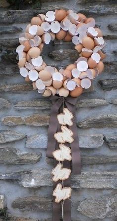 a wreath made out of eggs hanging on a stone wall