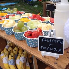 there are many bowls of fruit on display at the market table, including bananas and strawberries