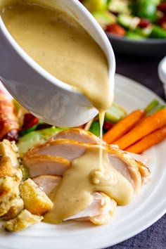 a person pouring gravy onto a plate of food