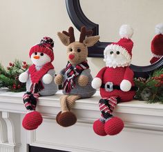 three knitted reindeers sitting on top of a mantle with christmas decorations around them