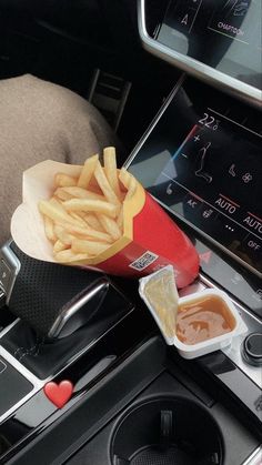 french fries and ketchup sit on the dashboard of a car