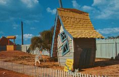 a small house with a thatched roof next to a white picket fence