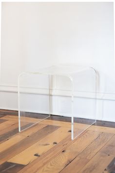 an acrylic table sitting on top of a hard wood floor