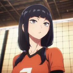 a woman in an orange shirt is standing by a volleyball net and looking at the camera