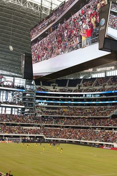 a stadium filled with lots of people watching soccer on large screen tvs above the stands