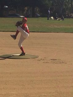 a young baseball player pitching a ball on top of a pitchers mound in a field