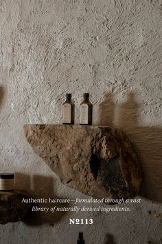 three bottles sitting on top of a stone shelf