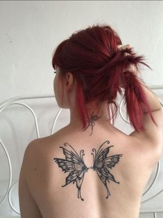 a woman with red hair has a butterfly tattoo on her back