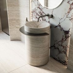 a bathroom with marble walls and flooring next to a round sink in the corner