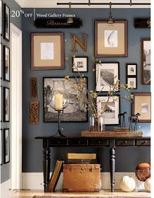 a table with some pictures on the wall above it and a vase filled with flowers