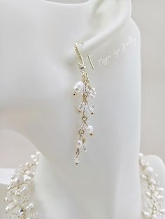 a white mannequin with some pearls on it's neck and a pair of earrings