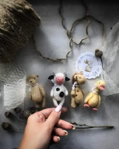 a hand holding a needle and some small stuffed animals