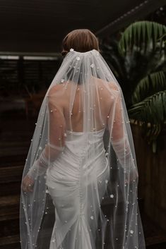 a woman in a wedding dress with a veil on her head is walking down the stairs