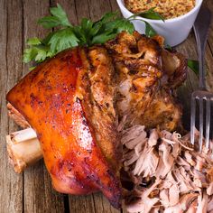 a large piece of meat sitting on top of a table next to a fork and bowl