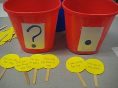 two red buckets with question signs on them sitting next to yellow cupcake top picks