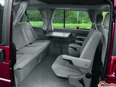 the interior of a van with two seats and a table in the back door area