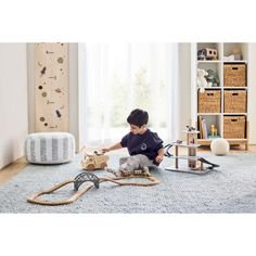 a young boy playing with his wooden train set in the living room on a rug