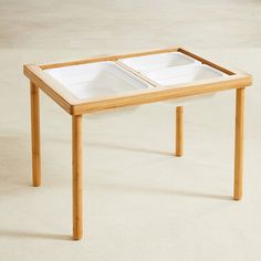 a wooden table with two white dishes on it's top and one is empty