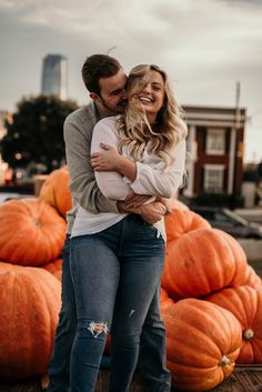 a man and woman hugging in front of pumpkins