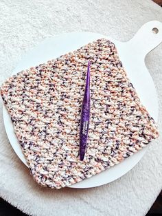 a crocheted dishcloth with a purple pen on it sitting on a white plate