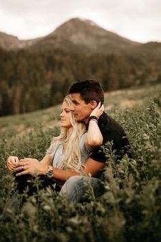 a man and woman are sitting in tall grass