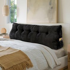 a bed with a black headboard in a bedroom next to a painting on the wall