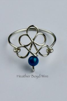 a ring with two hearts and a blue bead