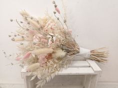 a bunch of dried flowers sitting on top of a white table next to a wall