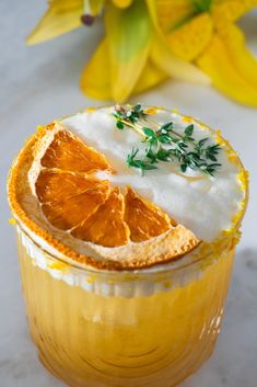 an orange slice sitting on top of a drink in a glass with whipped cream and sprigs