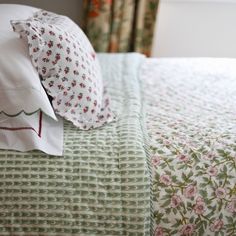 a bed with floral sheets and pillows on it