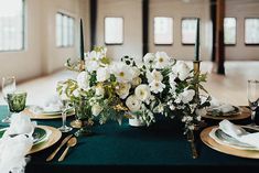 the table is set with white flowers and green linens for an elegant wedding reception