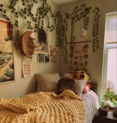 an unmade bed in a bedroom with plants on the wall and pictures above it