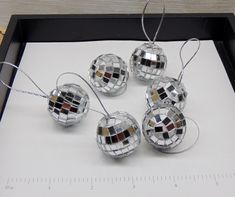 four shiny disco ball ornaments sitting on top of a piece of paper next to a ruler