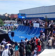 a group of people standing on top of a blue ramp next to a basketball court