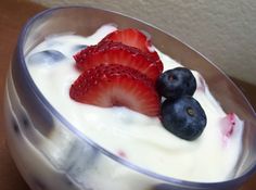 yogurt with strawberries and blueberries in a glass bowl on a table