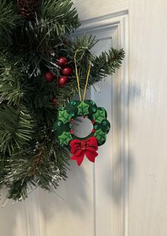 a christmas wreath hanging on the front door with red and green ornaments attached to it