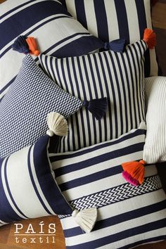 blue and white striped pillows with tassels on the ends are laying on a wooden floor