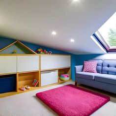 a room with a couch, bookshelf and pink rugs on the floor