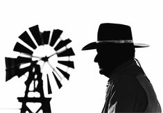 a man wearing a hat and standing next to a windmill in front of a white background