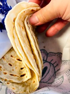 a person is holding some tortillas in their hand