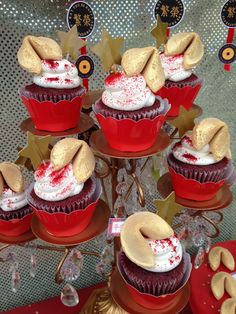 cupcakes with white frosting and sprinkles on top are displayed in red dishes