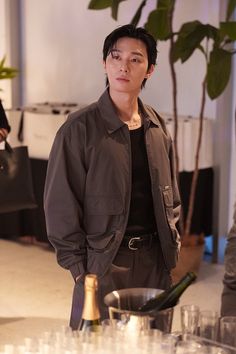 a man standing in front of a table filled with glasses and champagne bottles, looking at the camera