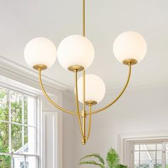 a chandelier hanging from the ceiling in a living room with white walls and windows