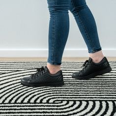 a person standing on top of a black and white rug