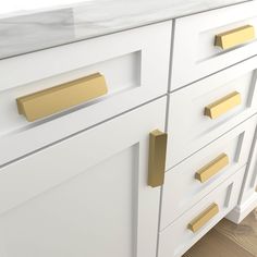 a white and gold bathroom vanity with marble counter top, brass handles and knobs