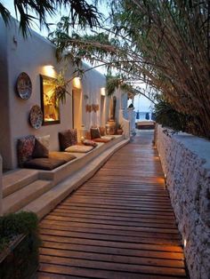 the walkway is lined with outdoor seating and plants on either side of the building, leading to an ocean view