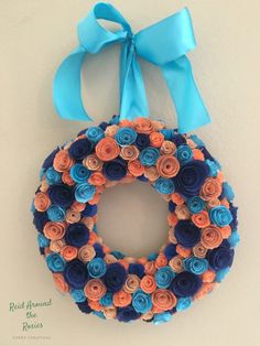 a blue and orange wreath hanging on the wall with a light blue ribbon around it