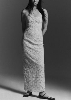 a woman in a long white dress posing for a black and white photo with her hands on her hips