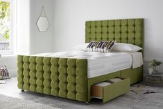 a bed with a green headboard and foot board in a room next to a window